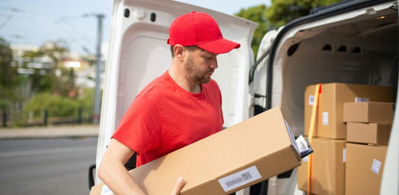 cardboard-ecommerce-packaging A courier unloading eCommerce packaging from a vehicle