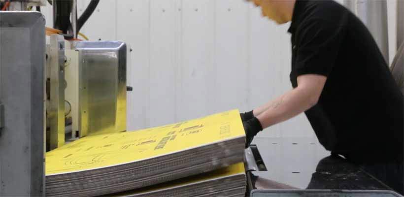 A person loading cardboard in to packaging manufacturing equipment