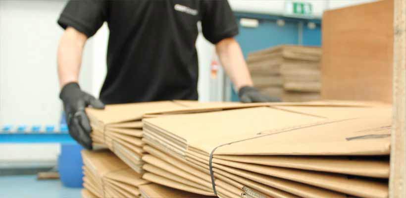 reseller-of-packaging A person stacking bundles of corrugated boxes