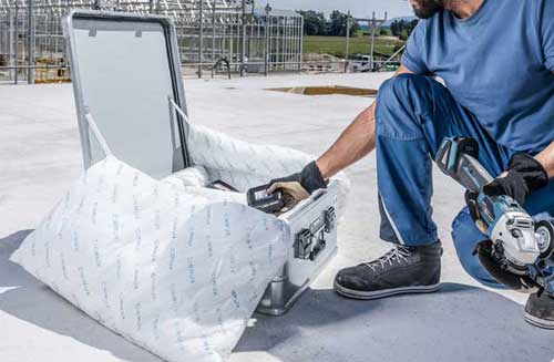 A workman putting a power tool in lithium battery shipping case