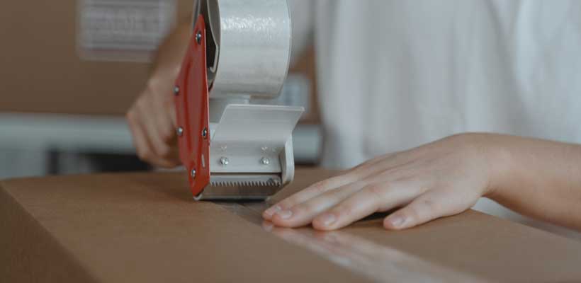 A person taping a large cardboard box