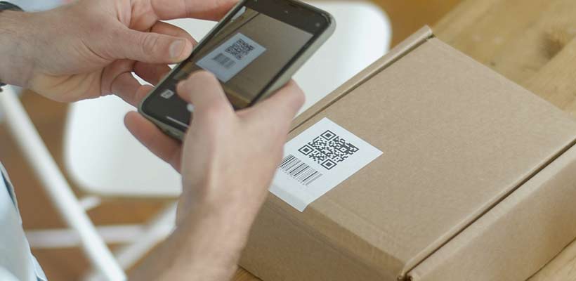 A person scanning a QR code on a packaging box