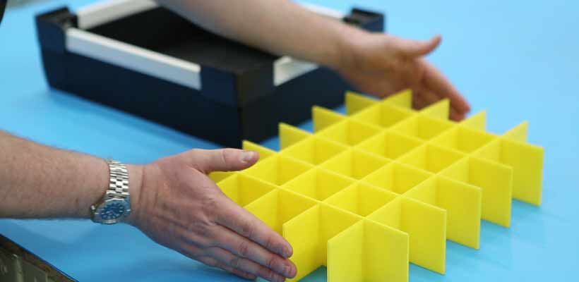 A production operative placing an assembled Correx divider set into a tote box