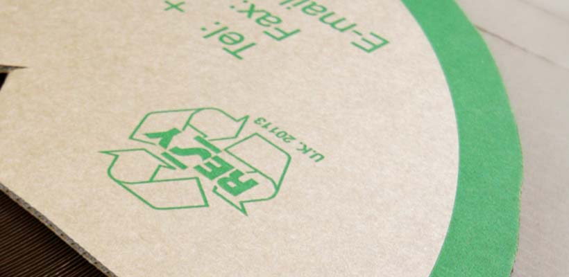 A green recycling symbol printed onto corrugated cardboard packaging.