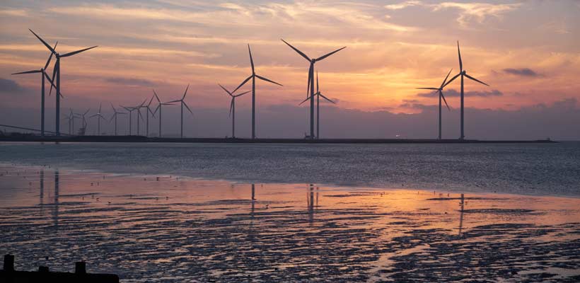 Silhouette of wind turbines against a setting sun