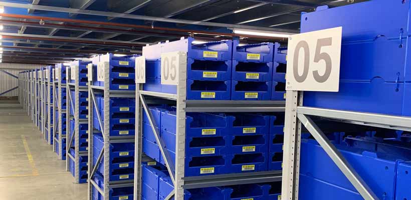 Rows of blue picking bins in warehouse racking