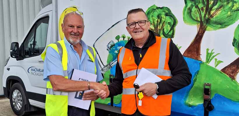 Two men shaking hands in front of a commercial vehicle