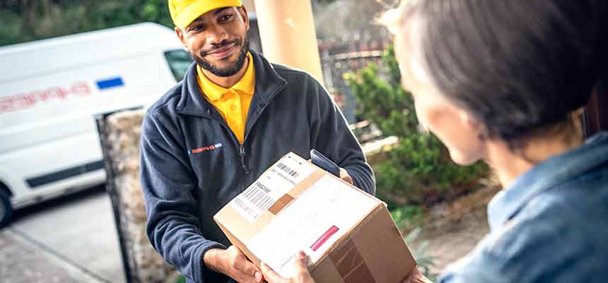recycled-cardboard-packaging A delivery driver handing over a cardboard box to a consumer.