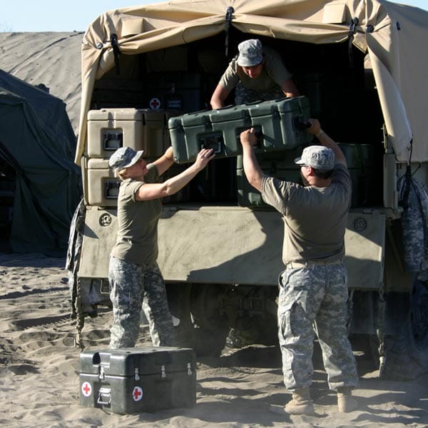 Military personnel unloading Hardigg cases from the back of a truck