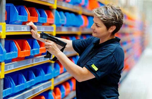 A person in a warehouse stood alongside a pick wall