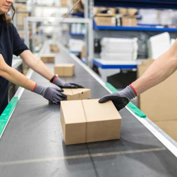 People in a fulfilment centre taking plastic free packaging off of a conveyor.