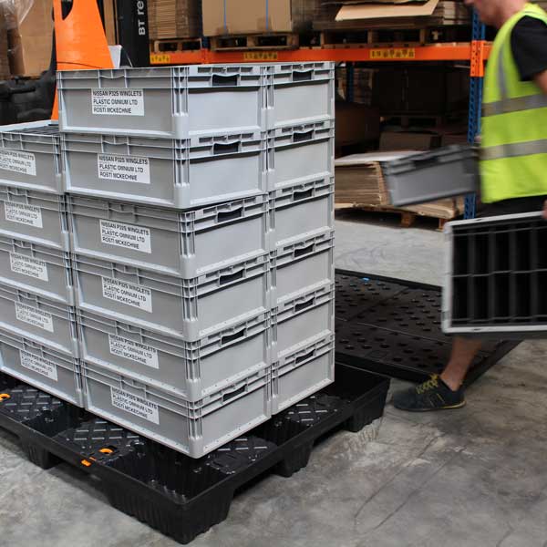 A person stacking reusable packaging on a pallet.