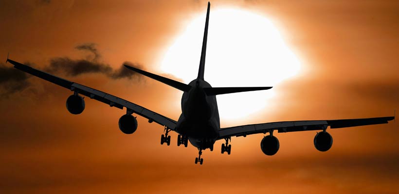 A sillhouette of a plane against a sunset