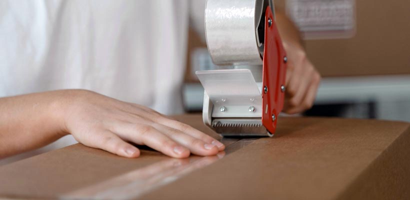 A person taping a postal box shut.