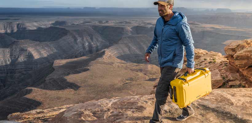 Nanuk A person carrying a Naunuk case whilst walking in mountains