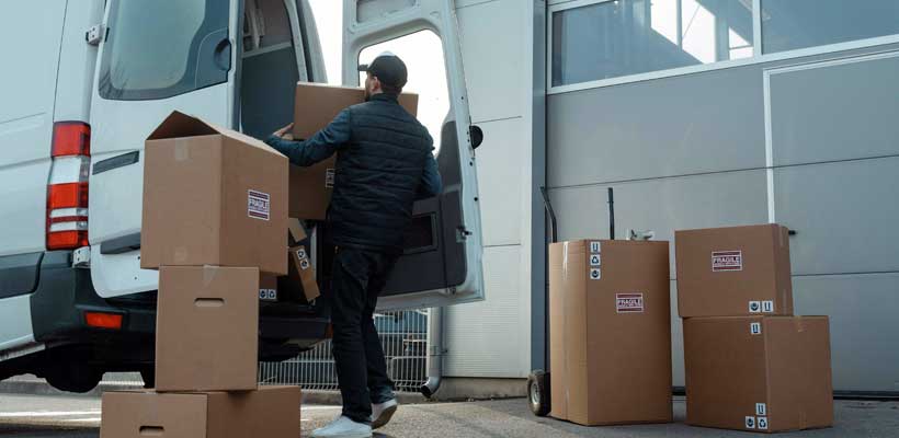 A person loading cardboard boxes into a van.