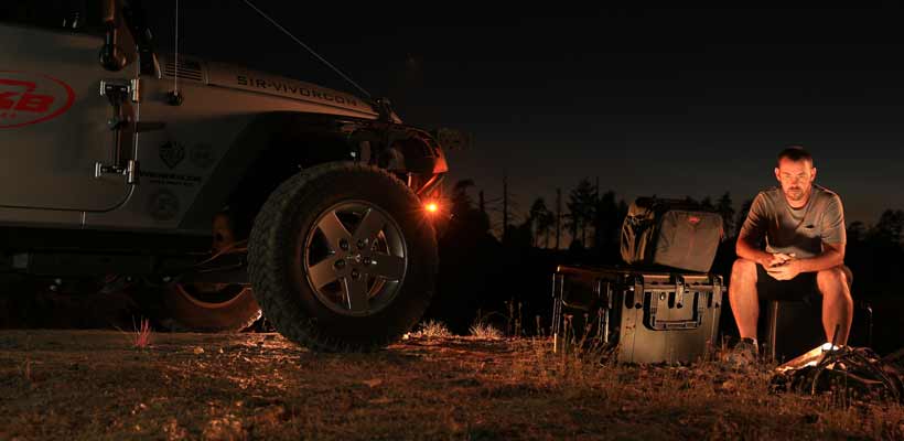 SKB 3i cases A person sat by a campfire with a number of SKB 3i cases