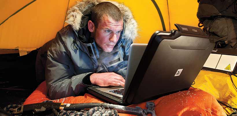 A person using a Peli laptop case inside a tent.