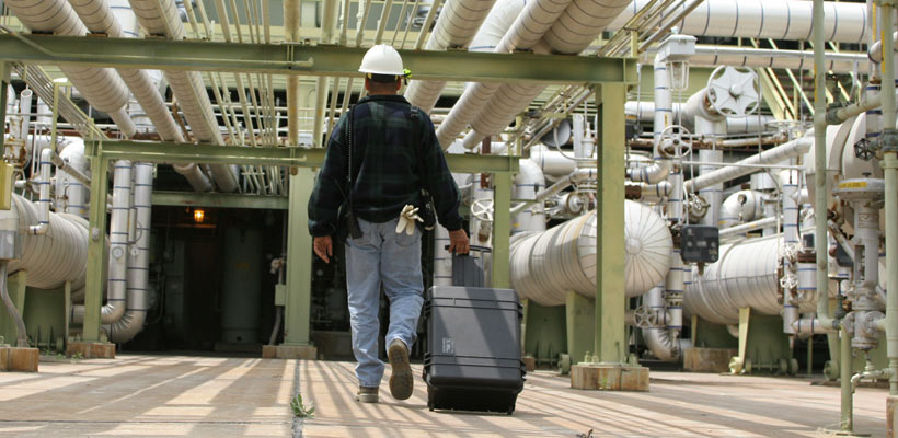 Large cases A workman pulling a large Peli case through an oil refinery
