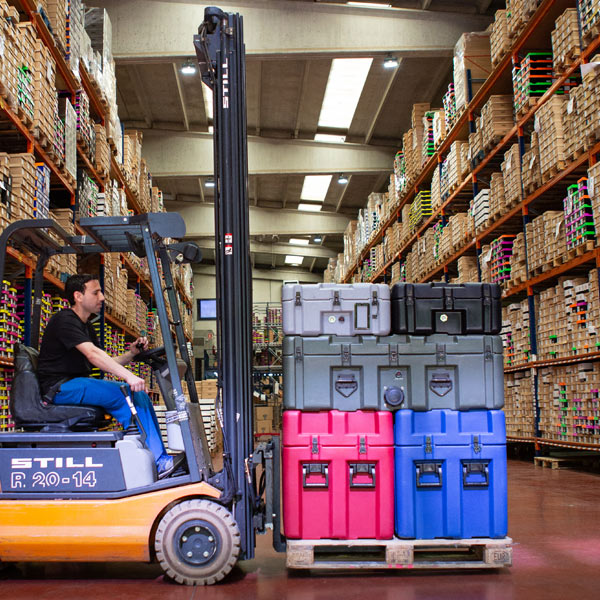 A forklift driver in a warehouse moving a pallet with transport cases stacked on it.